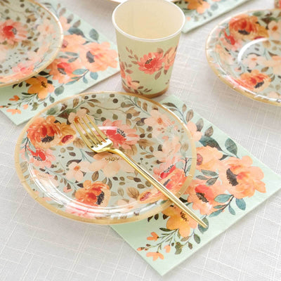 Floral disposable plates, cups, and napkins set for a party table setting.