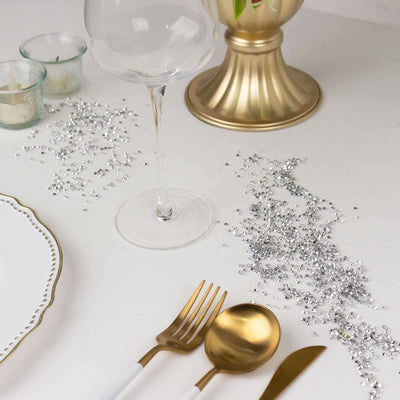 Elegant table setting with gold utensils, wine glass, and decorative elements.