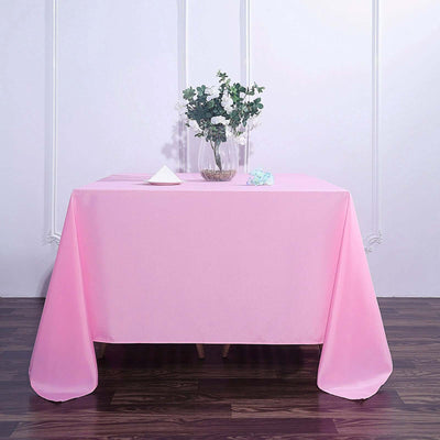 Pink tablecloth draped over a table with a vase of flowers