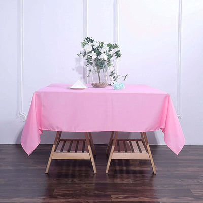 Pink tablecloth draped over a wooden table with a vase of flowers.