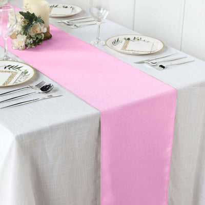 Pink table runner on a white table setting with elegant dinnerware.