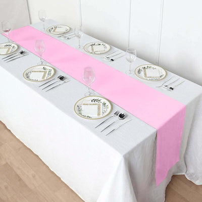 Pink table runner on a dining table set with elegant plates and glassware.