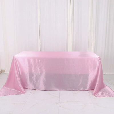 Pink satin tablecloth draped on a table in a studio setting.
