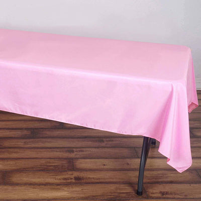 Pink tablecloth draped over a table on a wooden floor.