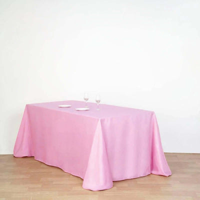 Pink tablecloth draped over a table with two plates and glasses