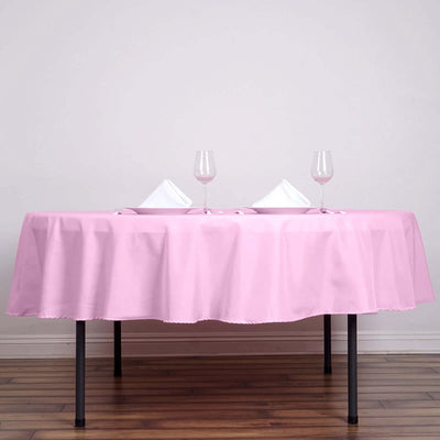 Pink tablecloth draped over a table set with glasses and napkins.