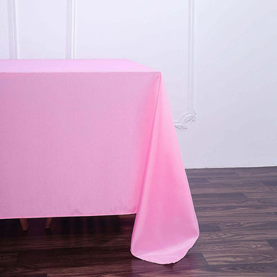 Pink tablecloth draped over a table against a plain backdrop.