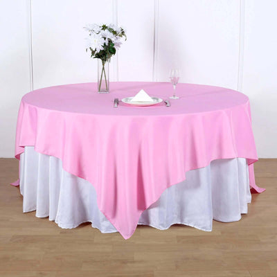 Pink tablecloth draped over a round table set for dining.