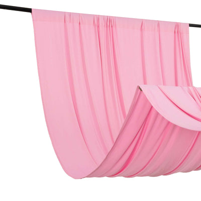 Pink drapery fabric hanging in soft folds against a plain backdrop