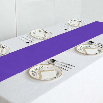 Purple table runner on a white table with decorative plates and utensils.