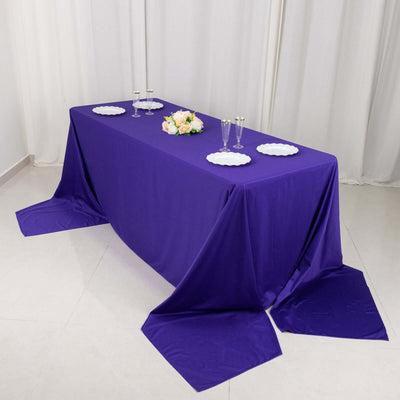Purple tablecloth draped elegantly over a table with plates and floral centerpiece.