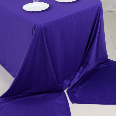 Purple tablecloth draped elegantly over a table with white plates.
