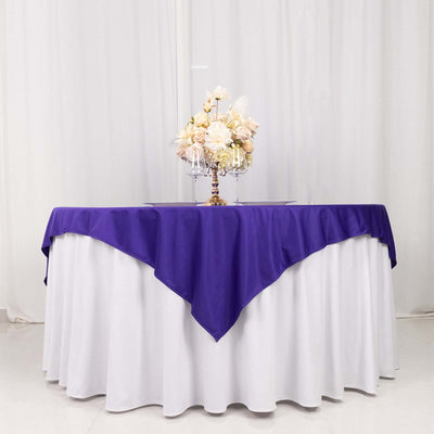 Purple tablecloth draped over a round table with floral centerpiece