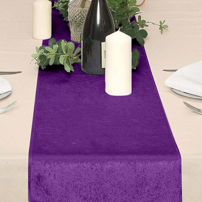 Purple table runner with candles and greenery on a dining table.