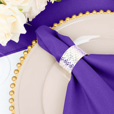 Purple napkin with silver ring on a decorative plate with floral accents.