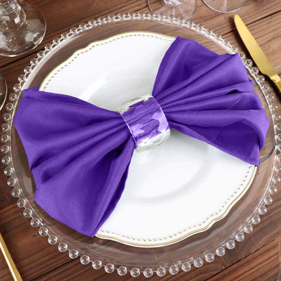 Purple bow napkin with a silver ring on an elegant plate setting.
