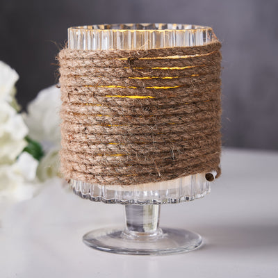 Glass candle holder wrapped in natural twine for rustic decor.