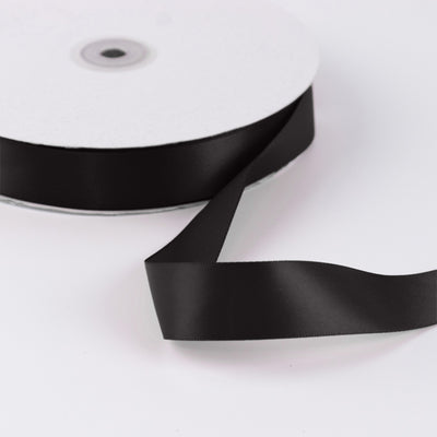 Black satin ribbon spool on white background