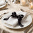 Elegant formal dinner table setting with white napkin and black ribbon bow