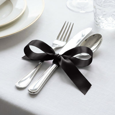 Elegant black ribbon tied around silver fork and spoon on a white table setting