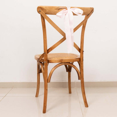 Wooden cross-back chair with a pink ribbon on the back.