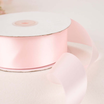 Pink satin ribbon on a spool with a flowing end