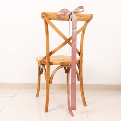 Wooden cross-back chair with pink ribbon bow, studio shot.