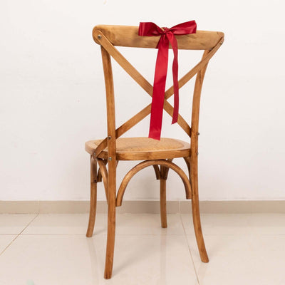 Wooden cross-back chair with a red ribbon bow on the back.