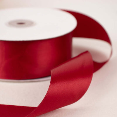 Red satin ribbon on a spool with a flowing end.