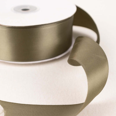 Olive green satin ribbon on a spool with a flowing ribbon