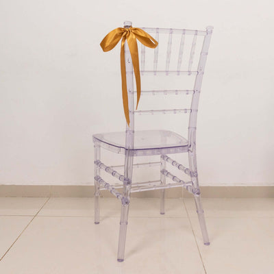 Clear chiavari chair with a gold ribbon bow on the back