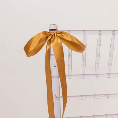 Gold satin ribbon tied on a clear chiavari chair.