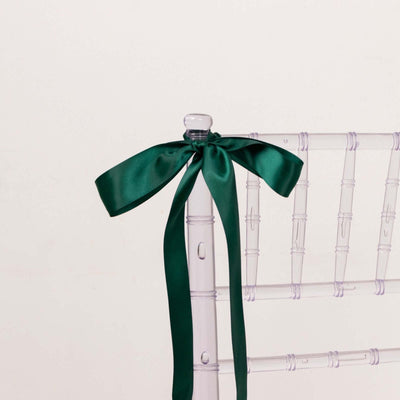 Green satin ribbon tied on a clear chiavari chair.