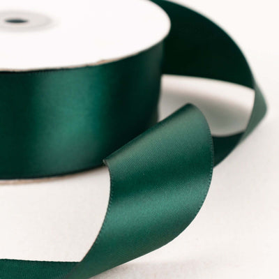 Green satin ribbon on a spool with a flowing end.