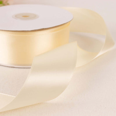 Cream satin ribbon on a spool with a flowing tail.
