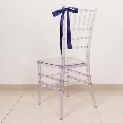Clear acrylic chair with a navy ribbon bow tied on the back.