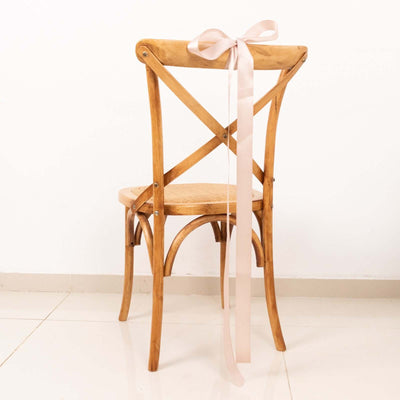 Wooden cross-back chair with a pink ribbon bow on a white background