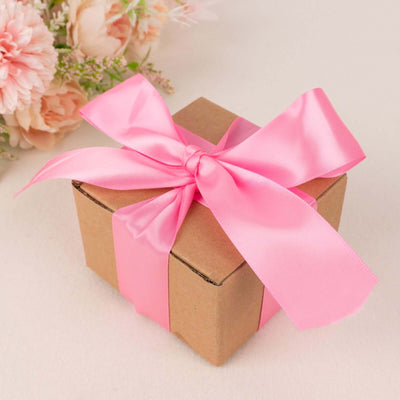 Gift box with pink ribbon and flowers in the background.