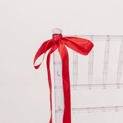 Clear chiavari chair with a red satin ribbon tied on the back.