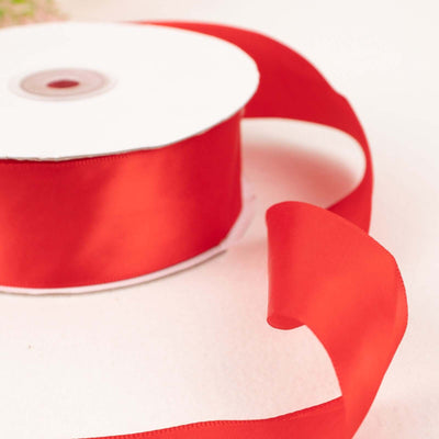 Red satin ribbon on a spool with a flowing tail
