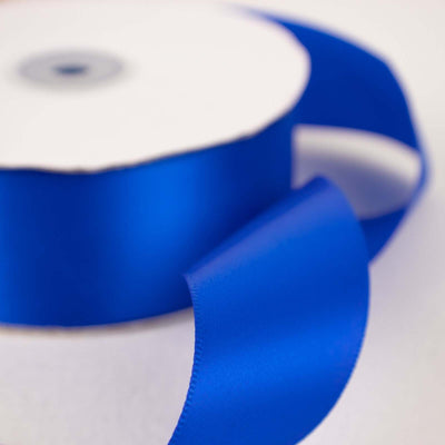 Blue satin ribbon on a spool with a smooth finish.