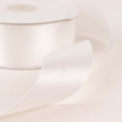 White satin ribbon on a spool with a flowing end.