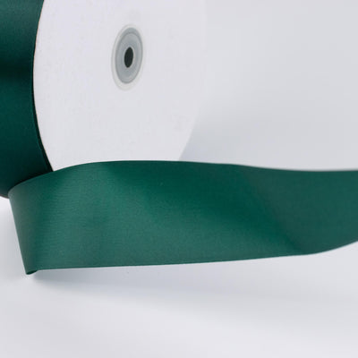 Green satin ribbon spool close-up on white background