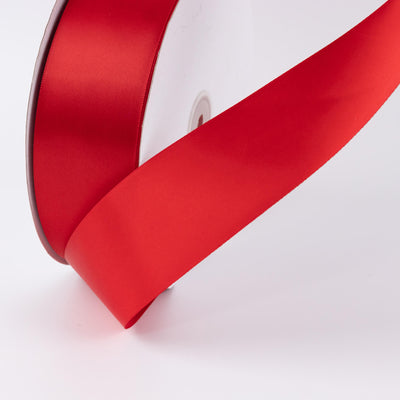 Red satin ribbon spool close-up on white background