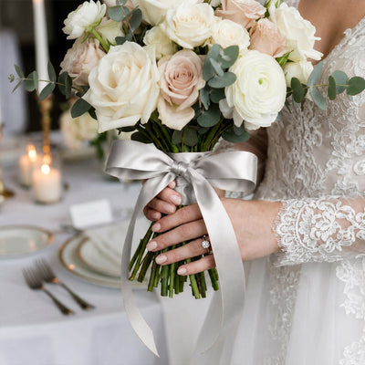 Bride holding ivory rose wedding bouquet with eucalyptus and satin ribbon