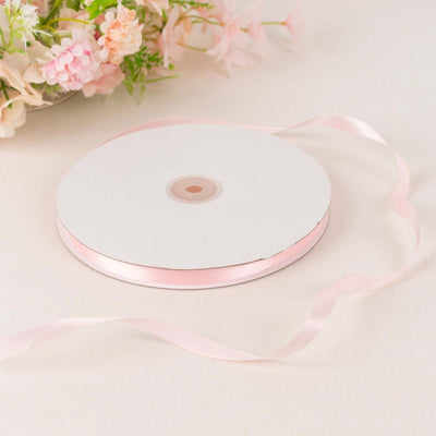 Pink satin ribbon roll on a white background with floral decor.