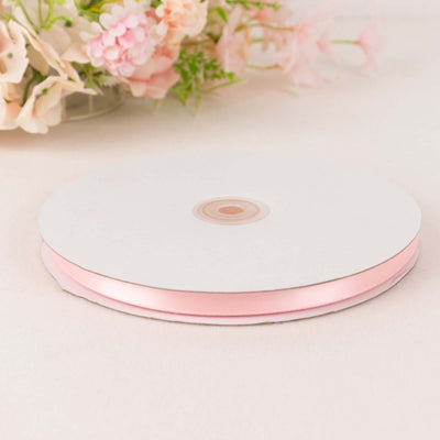 Pink satin ribbon roll on a white background.