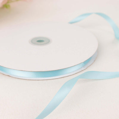 Light blue satin ribbon on a spool against a plain background
