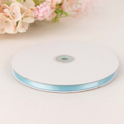 Light blue satin ribbon on a spool with a plain white background