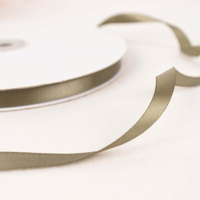 Olive green satin ribbon roll with loose ribbon strands